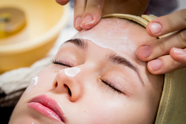 Cosmetologist doing facial mask to face of woman — Stock Photo, Image