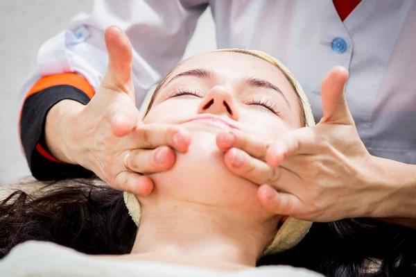 As mãos de cosmetologist aplicam a nata à cara da mulher . — Fotografia de Stock