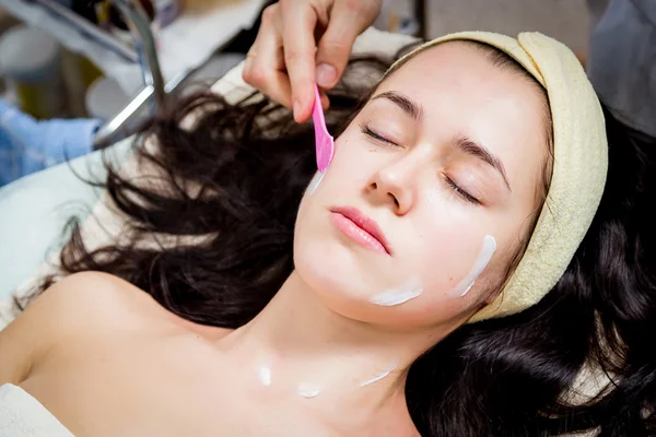 Cosmetologist doing facial mask to face of woman — Stock Photo, Image