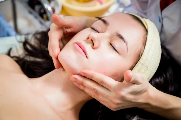 As mãos de cosmetologist aplicam a nata à cara da mulher . — Fotografia de Stock