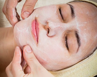 여자의 얼굴에 크림을 적용 하는 미용사