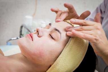 여자의 얼굴에 크림을 적용 하는 미용사