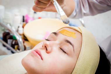 여자의 얼굴에 크림을 적용 하는 미용사