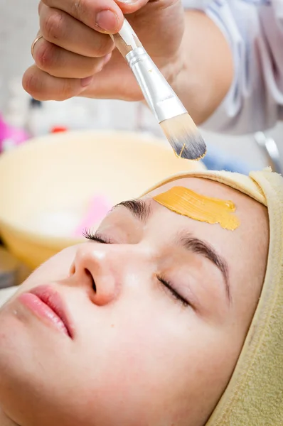 Schoonheidsspecialist toepassing crème op het gezicht van vrouw — Stockfoto