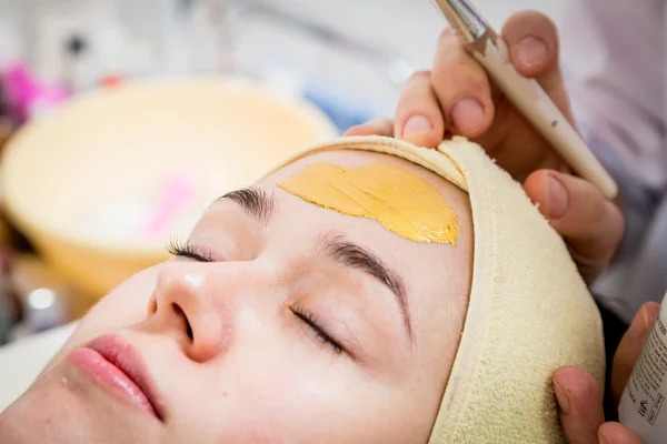 Косметолог наносит крем на лицо женщины — стоковое фото