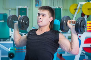 Dambıllarla egzersiz yapan adam.