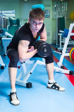 Dambıllarla egzersiz yapan adam.