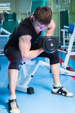 Dambıllarla egzersiz yapan adam.