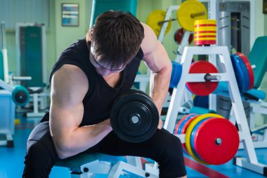 Dambıllarla egzersiz yapan adam.