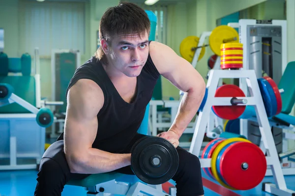 Dambıllarla egzersiz yapan adam.