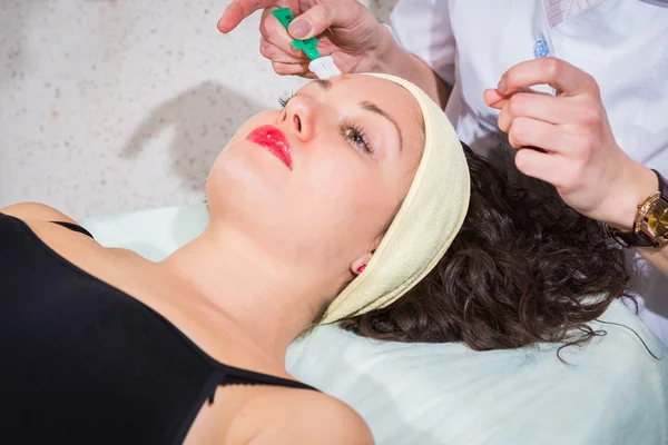 Cosmetologue appliquer la crème sur le visage de la femme — Photo