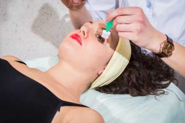 Il cosmetologo applica la crema a faccia di donna — Foto Stock