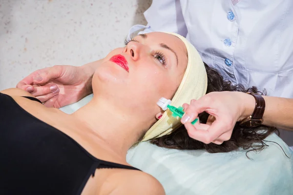 Cosmetologist aplicam a nata à cara da mulher — Fotografia de Stock