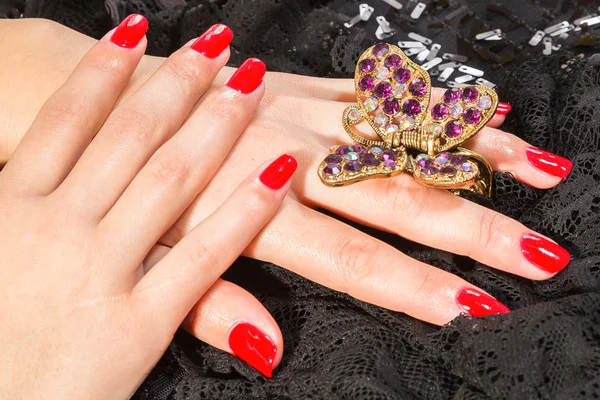 Manos femeninas con manicura roja y barreta de mariposa — Foto de Stock