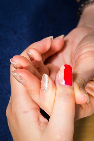 Esteticista aplicando verniz de unhas vermelhas nas unhas de um cliente — Fotografia de Stock