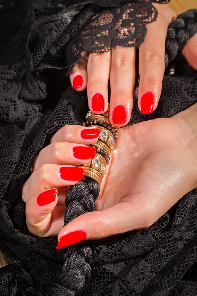 Female hands with red manicure on a black lace — Stock Photo, Image