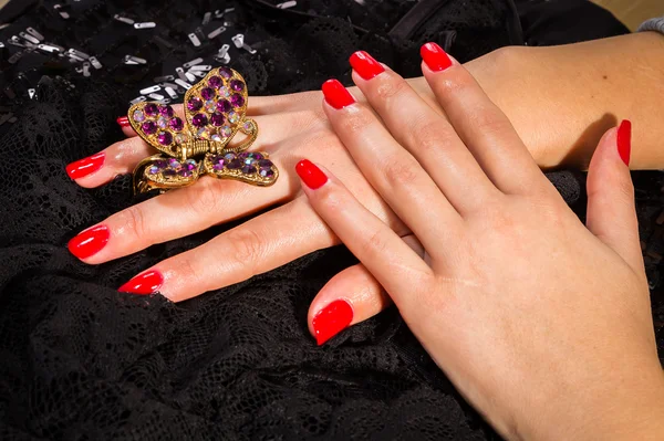 Female hands with red manicure and butterfly barrette — Stock Photo, Image