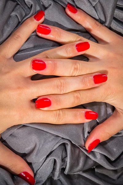 Mooie vrouwelijke handen met rode nagellak op de nagels — Stockfoto