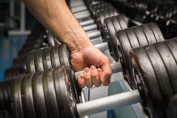 Homme faisant des exercices avec haltère dans la salle de gym . — Photo