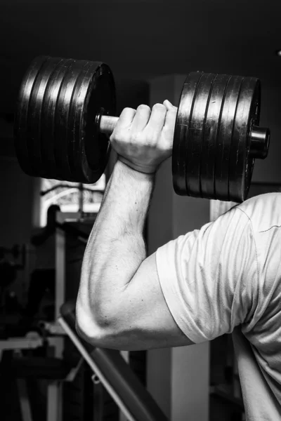 Hombre haciendo ejercicios con mancuerna en el gimnasio —  Fotos de Stock