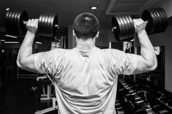 Hombre haciendo ejercicios con mancuerna en el gimnasio — Foto de Stock