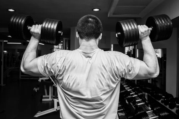 Uomo che fa esercizi con manubri in palestra — Foto Stock