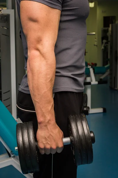 Man in een sportschool met halters — Stockfoto