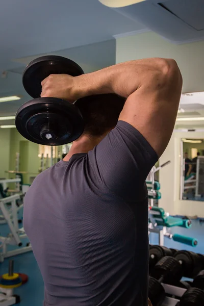 Homme dans une salle de gym avec haltères — Photo