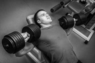 Dambıllarla egzersiz yapan adam.