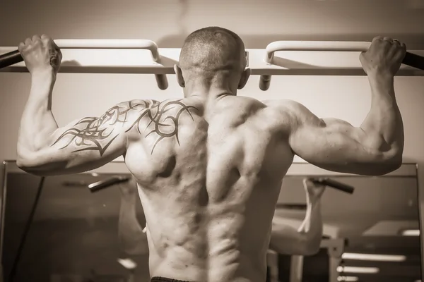 Homme avec un tatouage exercice dans la salle de gym — Photo