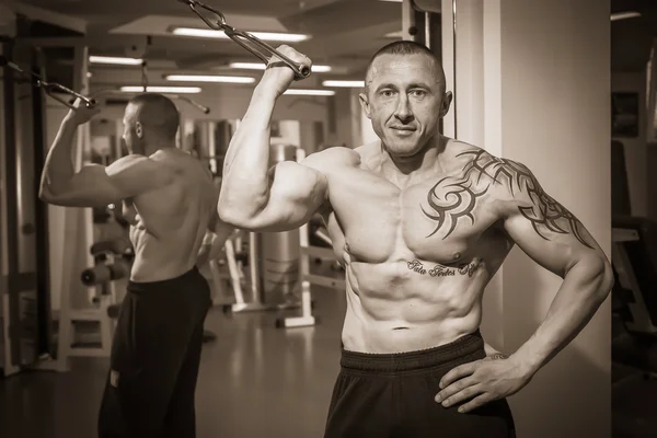 Homem com uma tatuagem exercitando-se no ginásio — Fotografia de Stock