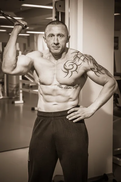 Hombre con un tatuaje haciendo ejercicio en el gimnasio —  Fotos de Stock
