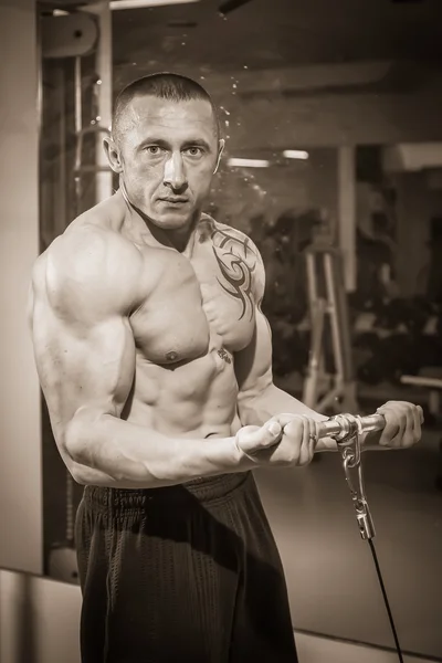 Hombre con un tatuaje haciendo ejercicio en el gimnasio —  Fotos de Stock