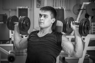 Dambıllarla egzersiz yapan adam.