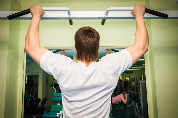 Man performs sport exercises on horizontal bar — Stock Photo, Image