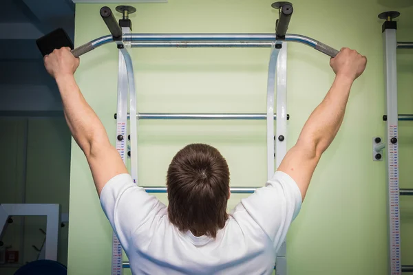 Homem realiza exercícios esportivos na barra horizontal — Fotografia de Stock