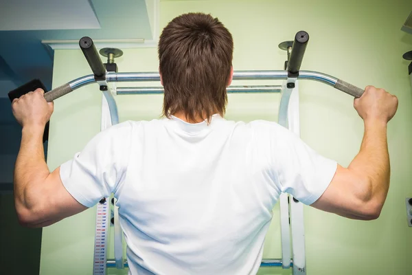 Homem realiza exercícios esportivos na barra horizontal — Fotografia de Stock