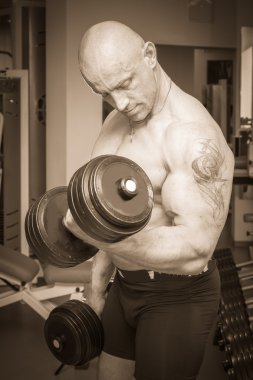 Dambıllarla egzersiz yapan adam.