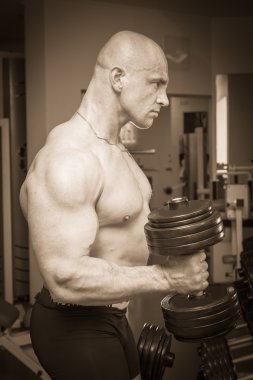 Dambıllarla egzersiz yapan adam.