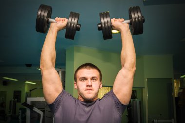 Dambıllarla egzersiz yapan adam.