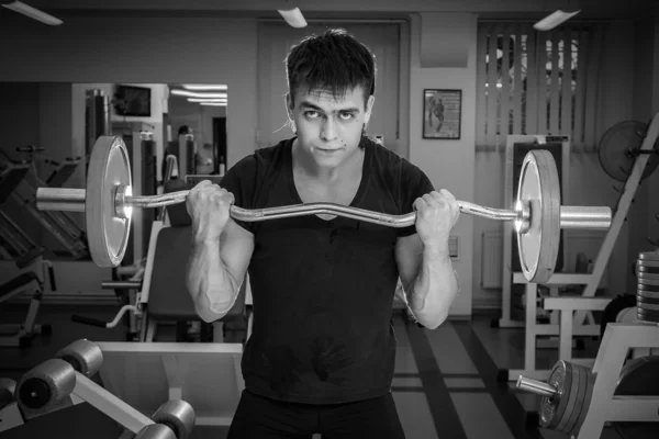 Man opleiding met atletische barbell in gym — Stockfoto