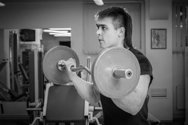 Man opleiding met atletische barbell in gym — Stockfoto