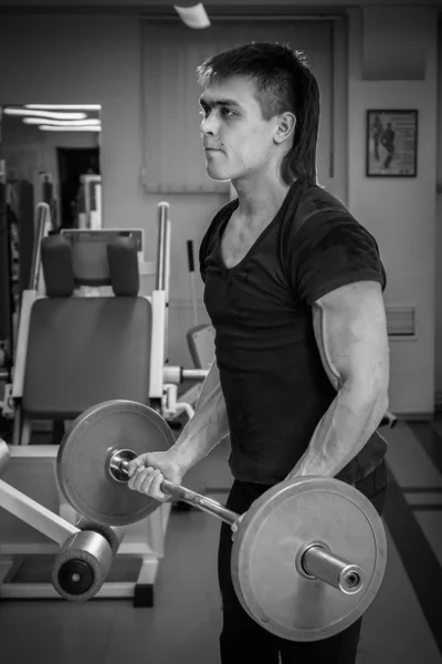 Man opleiding met atletische barbell in gym — Stockfoto