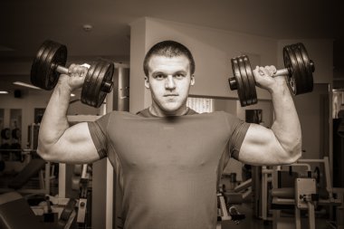 Dambıllarla egzersiz yapan adam.