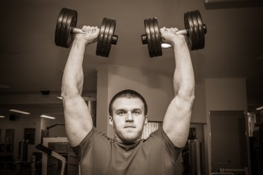 Dambıllarla egzersiz yapan adam.