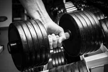 Dambıllarla egzersiz yapan adam.