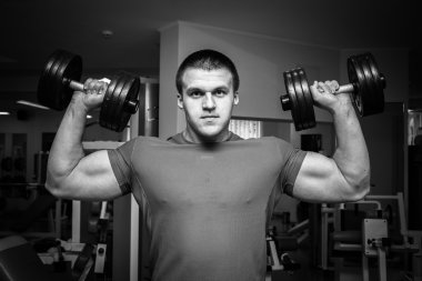 Dambıllarla egzersiz yapan adam.