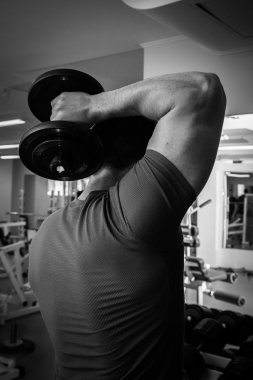 Dambıllarla egzersiz yapan adam.