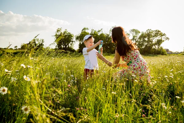 Moeder en zoon spelen in een veld — Stockfoto