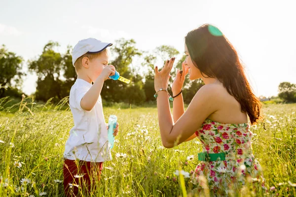 Мама грає з сином з мильними бульбашками — стокове фото